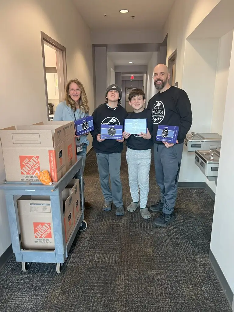 four people smiling and holding up Share Care Book Boxes